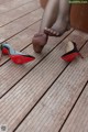 A woman's feet in high heels on a wooden deck.