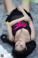 A woman laying on the floor in a black and pink lingerie.