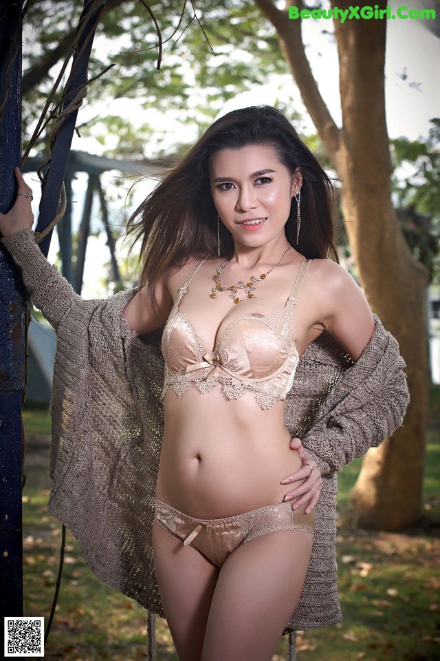 A woman in lingerie leaning against a tree.