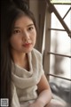 A woman with long black hair sitting on a window sill.