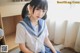 A woman in a school uniform sitting on the floor.