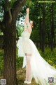 A woman in a wedding dress standing next to a tree.