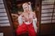 A woman in a red and white outfit sitting on a wooden floor.