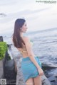 A woman in a blue and green bikini standing by the ocean.