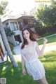 A woman in a white dress standing in the grass.