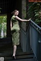 A woman in a green dress standing on a set of stairs.