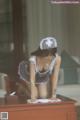 A woman in a nurse outfit kneeling on a desk.