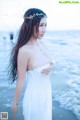 A woman in a white dress standing on a beach.