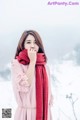 A woman in a pink dress and red scarf in the snow.