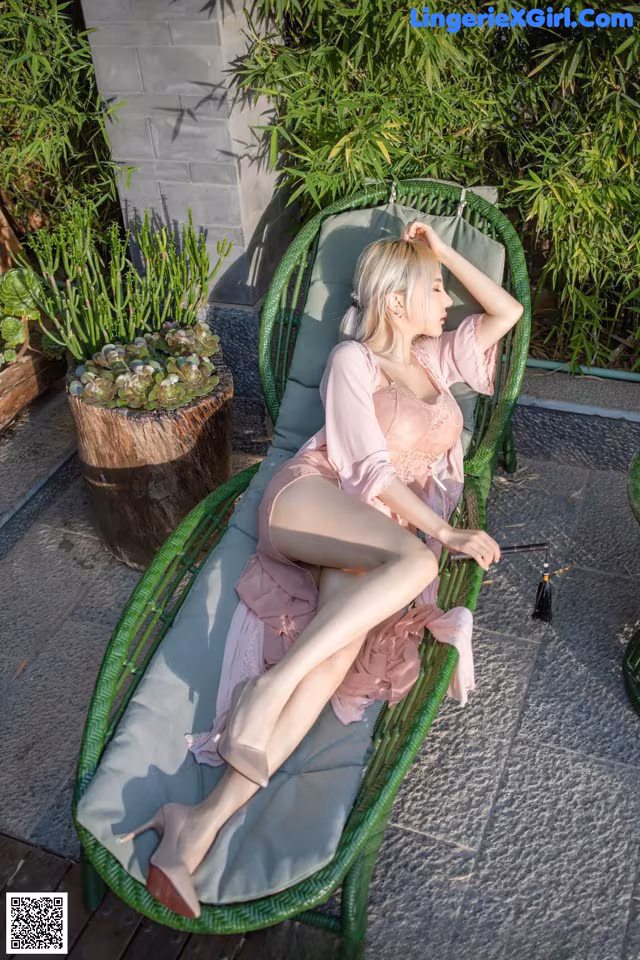 A woman in a pink dress sitting on a green chair.