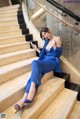 A woman in a blue dress sitting on a set of stairs.