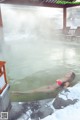 A woman in a red bikini laying in a hot spring.