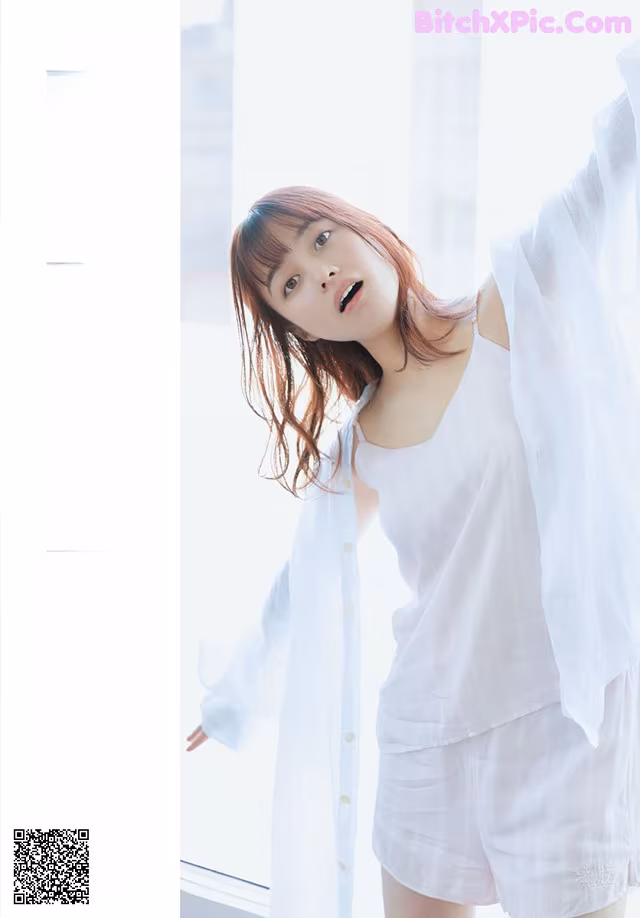 A woman in a white shirt and shorts posing for a picture.