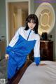 A woman in a blue and white track suit posing on a bed.