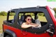 A woman sitting in the driver's seat of a red jeep.