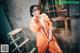 A woman in an orange jumpsuit posing for a picture.