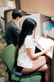 A woman sitting at a desk writing in a notebook.